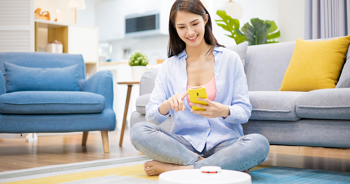 Woman controlling robot vacuum cleaner